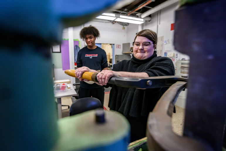 graduate student Martha Larkin pulls a lever to operate a hand press